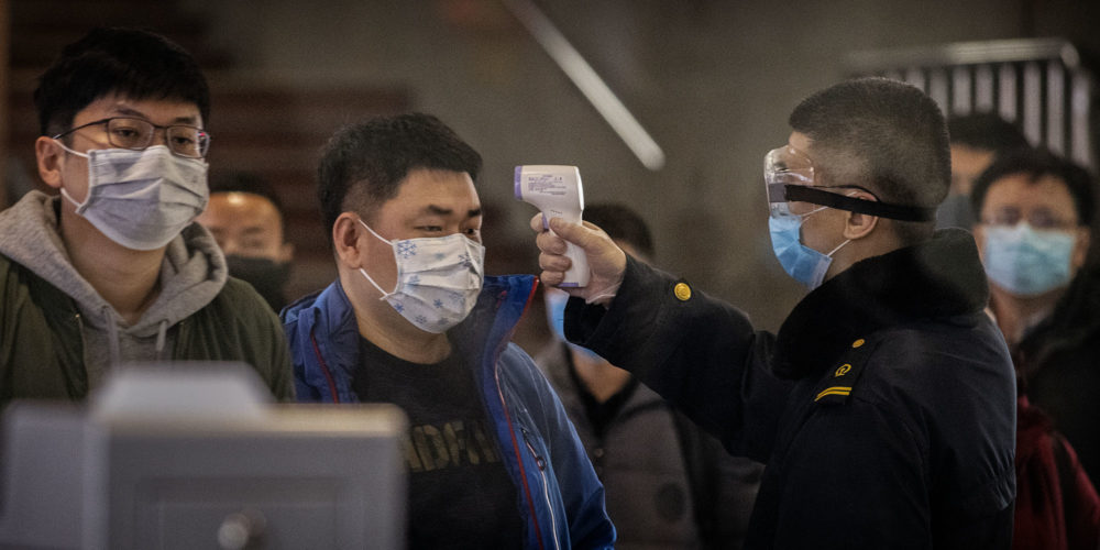 A Chinese passenger that just arrived on the last bullet train from Wuhan to Beijing is checked for a fever by a health worker at a Beijing railway station on January 23, 2020 in Beijing, China. (Photo: Kevin Frayer/Getty Images)